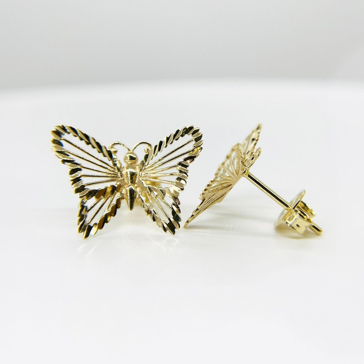 Front and side view of gold classic textured butterfly stud earrings on white background.