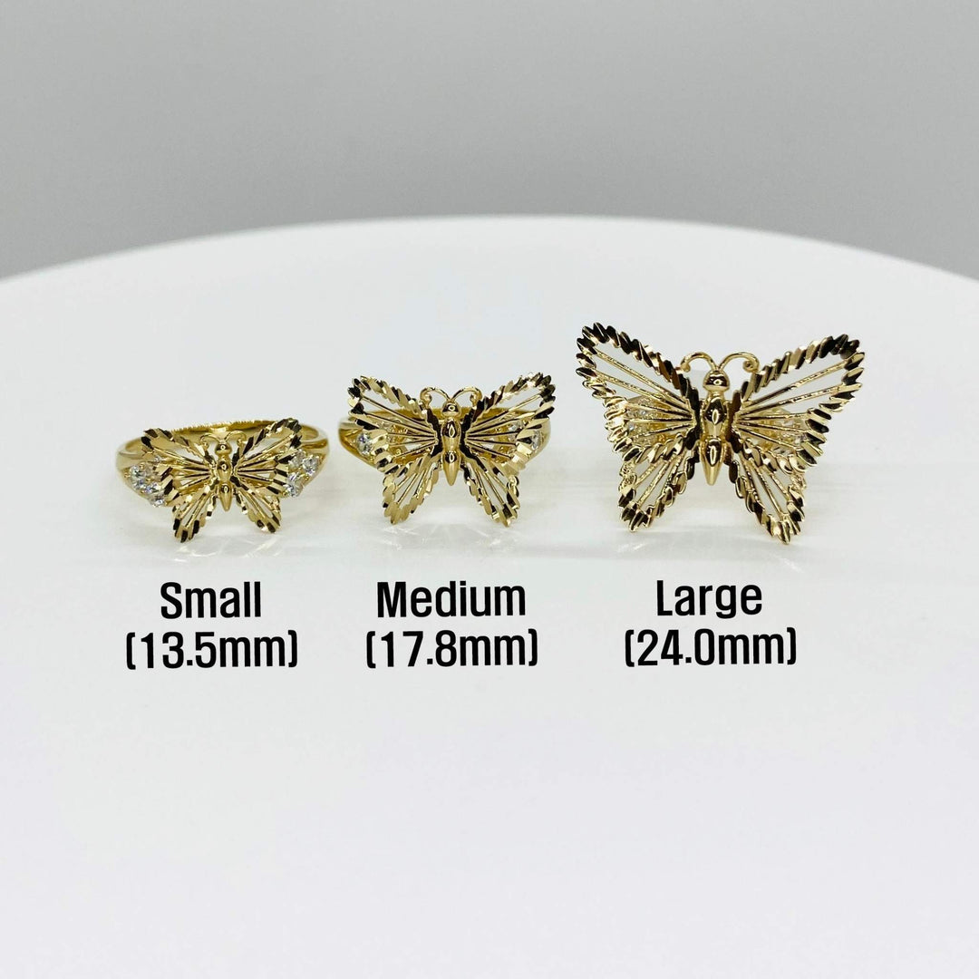 Three 10k - 14k gold butterfly shaped rings in different sizes on a white surface.