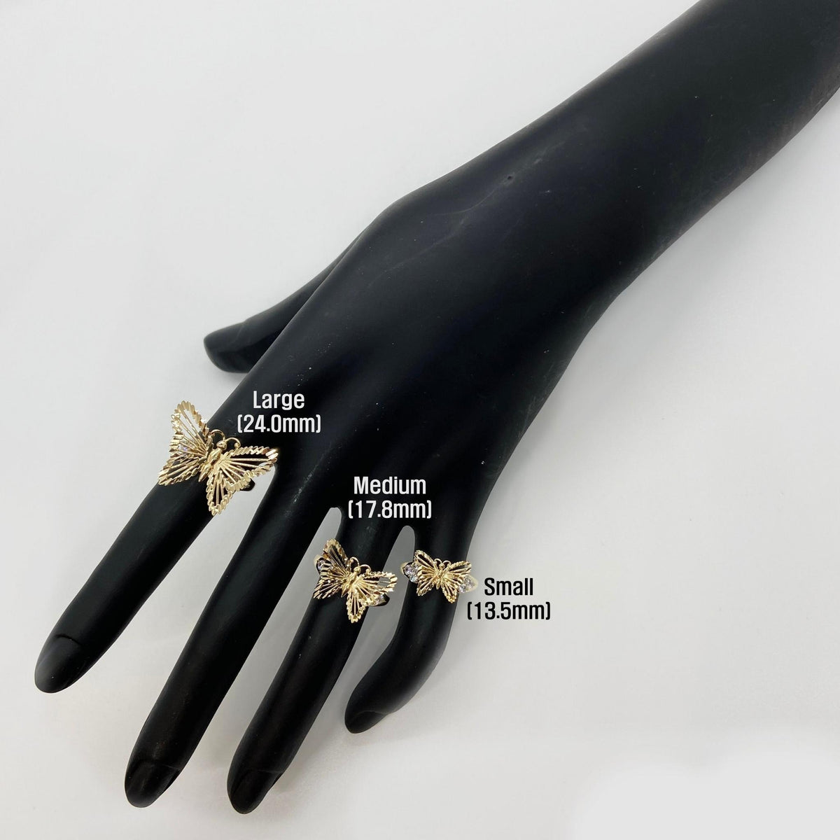 three 10k - 14k gold Butterfly shaped rings on a black mannequin hand.