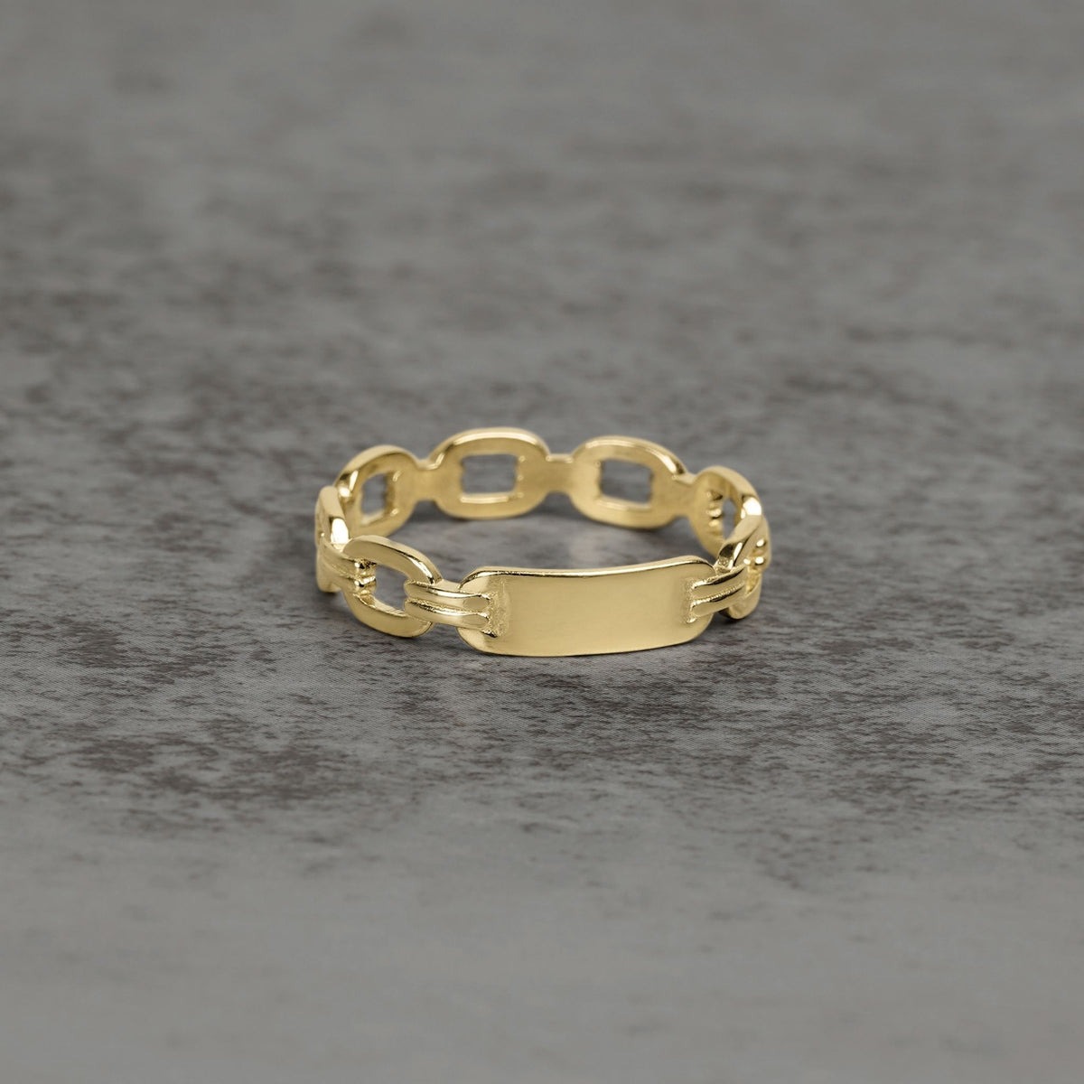Close-up of a yellow gold ID ring featuring a polished center nameplate.