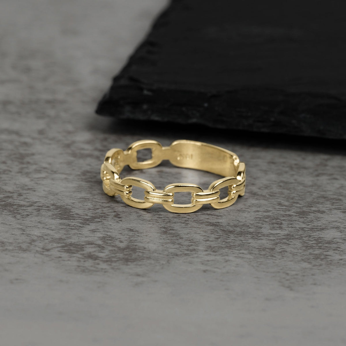 Solid 10k or 14k gold classic Rolo chain link ring on a gray surface.