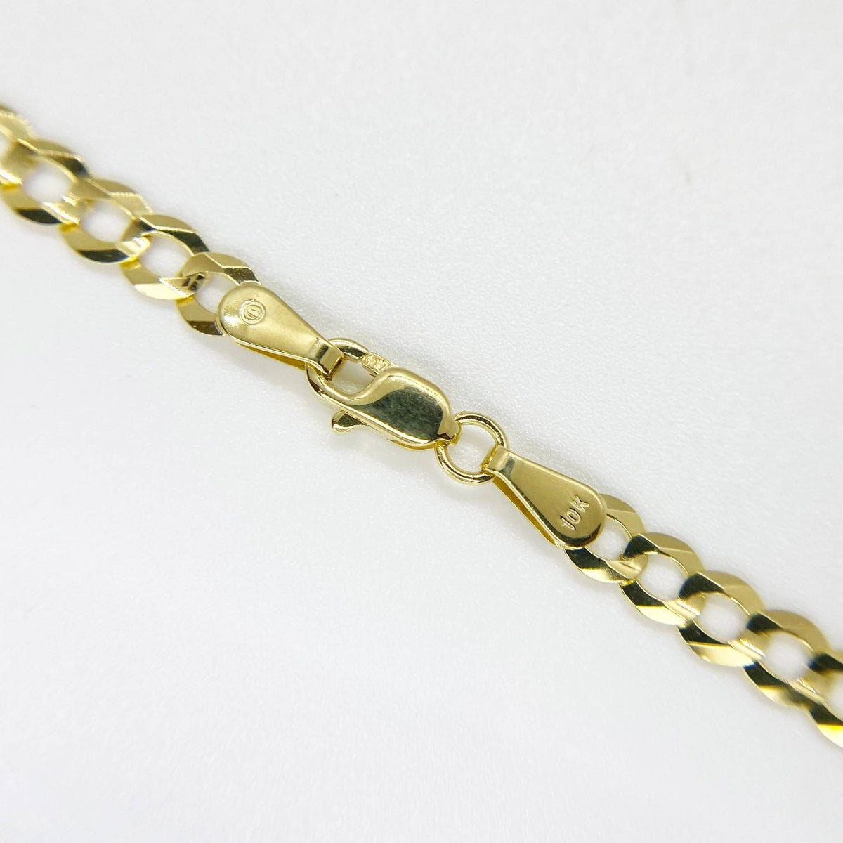 Close-up of a solid gold classic Cuban curb chain showing the lobster clasp.