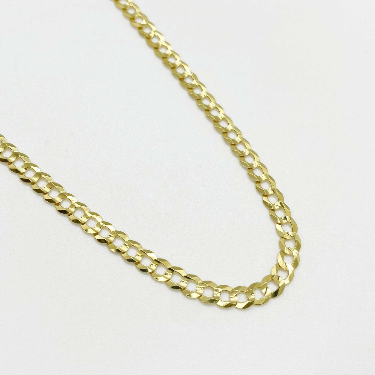 Polished yellow gold classic Cuban curb chain necklace on white background.