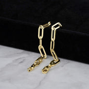 Close-up of two hollow yellow gold paperclip bracelets showing lobster claw clasps.