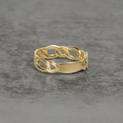 Detailed product view of a gold chain-link ring resting on a textured surface.