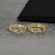 Close-up of two yellow gold chain-link style rings displayed on a gray surface.