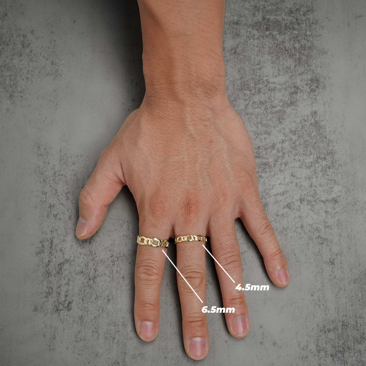 Hand wearing two gold Figaro band rings with size measurement labels for 4.5mm and 6.5mm.