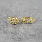 Two gold rings with floral designs on a gray background