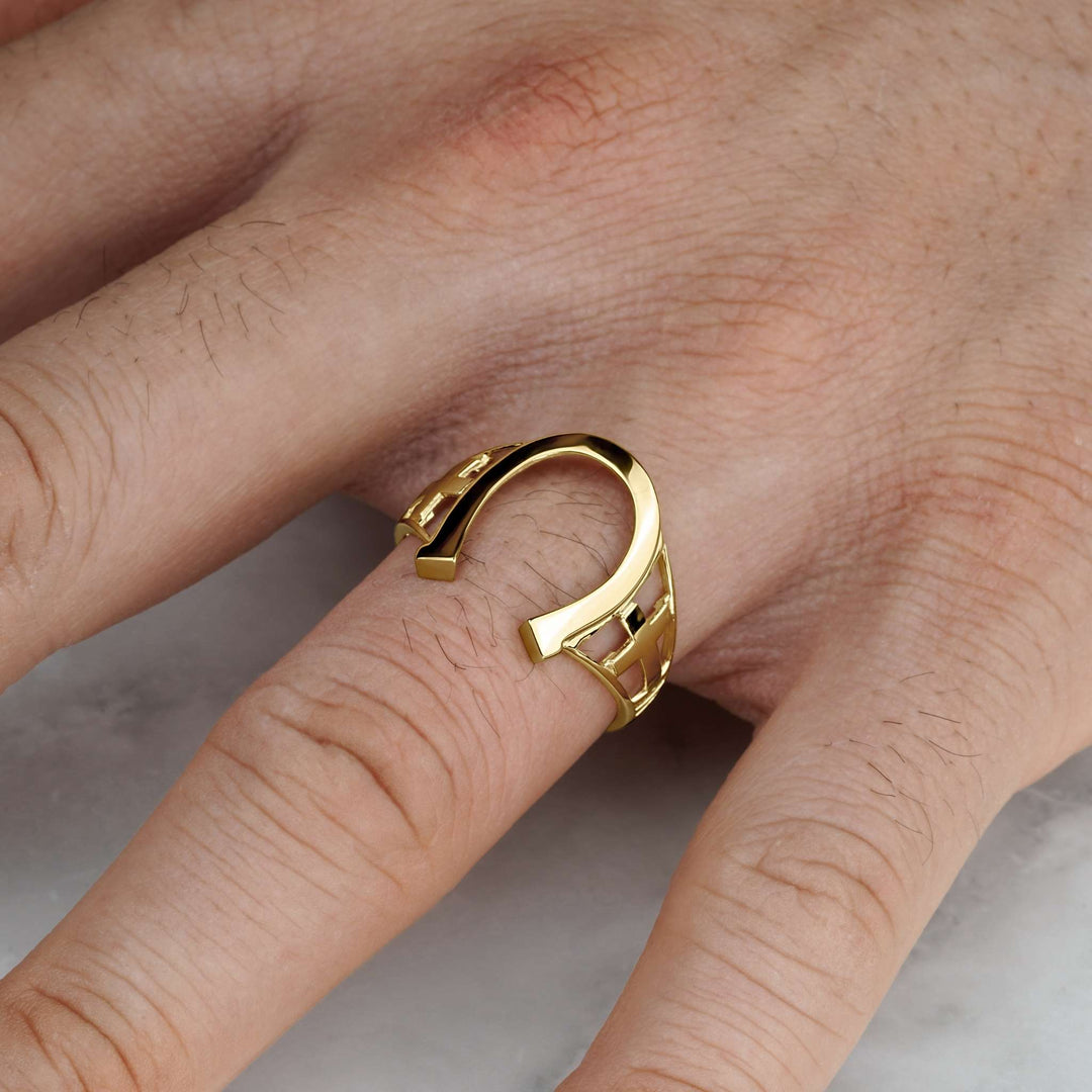 High-polish gold horseshoe signet ring shown worn on a man's finger.