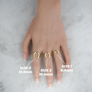 Top-down lifestyle view of three gold horseshoe rings with millimeter size labels.
