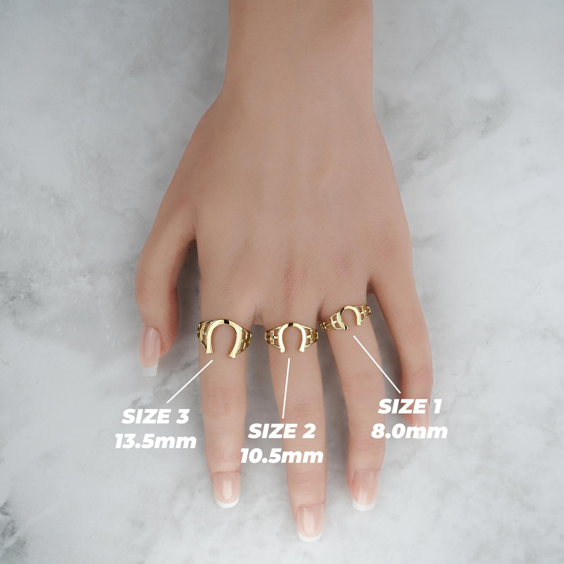 Top-down lifestyle view of three gold horseshoe rings with millimeter size labels.