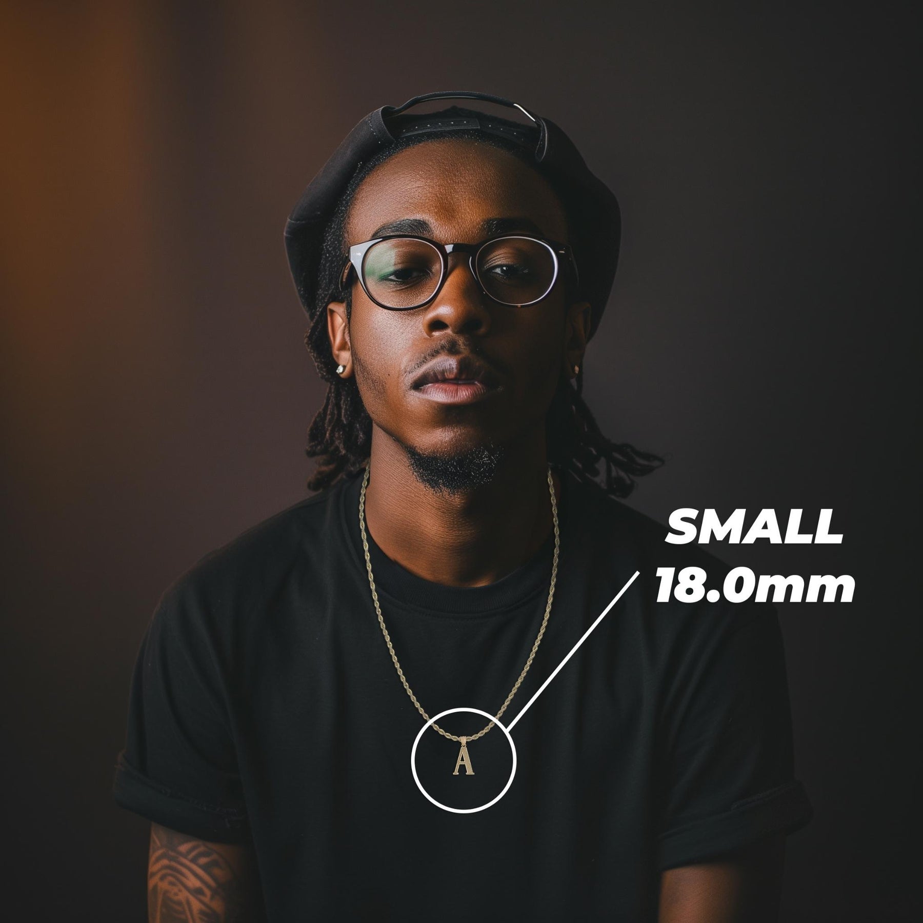 Model wearing a small 18mm gold initial 'A' pendant labeled SMALL 18.0mm on a black shirt.