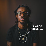 Model wearing a large 32mm gold initial 'A' pendant labeled LARGE 32.0mm on a black shirt.