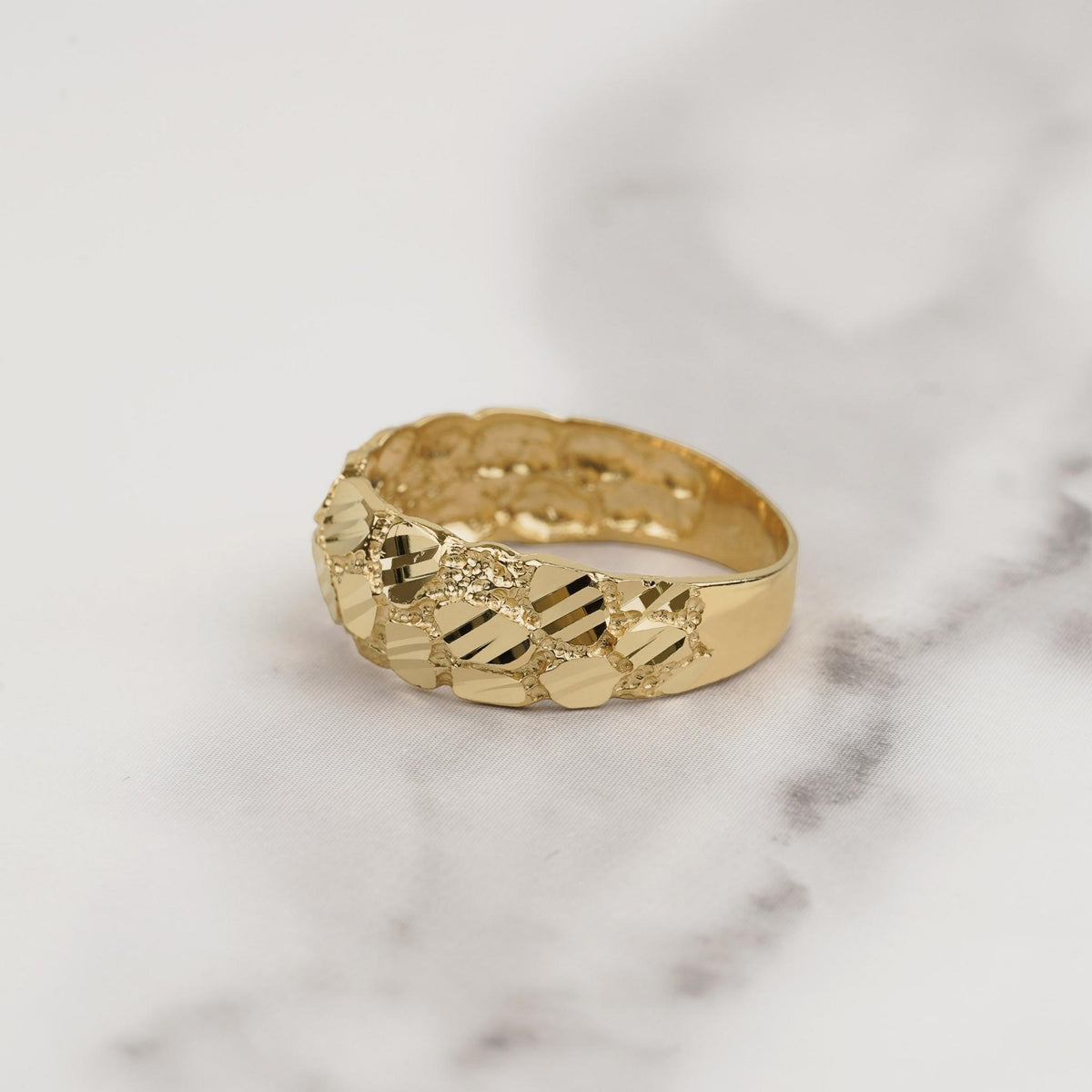 Textured 10k or 14k gold classic nugget band ring displayed on marble.