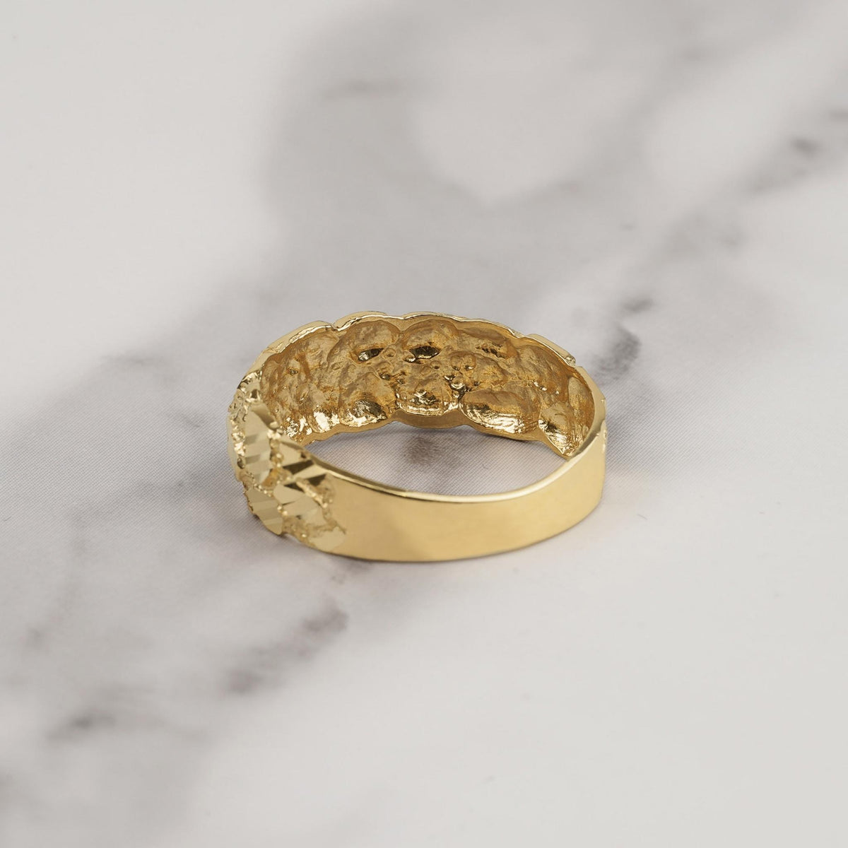 Rear interior view showing smooth band profile of a gold classic nugget ring on marble.