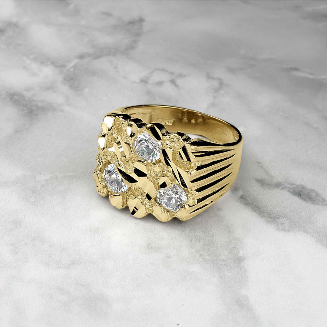 Square gold nugget ring with three clear CZ stones on a marble background.