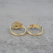 Two 10k - 14k gold rings with floral design back view on a gray surface