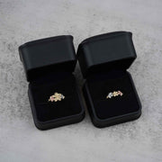 Two 10k - 14k gold rings with a floral design in black jewelry boxes on a gray surface