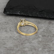 Back view of a gold three-stone ring with an oval center stone on gray stone.
