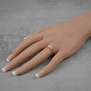 Side view of a gold three-stone ring with an oval diamond on a model's hand.