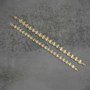 Back view of two gold nugget heart link bracelets on a gray background.