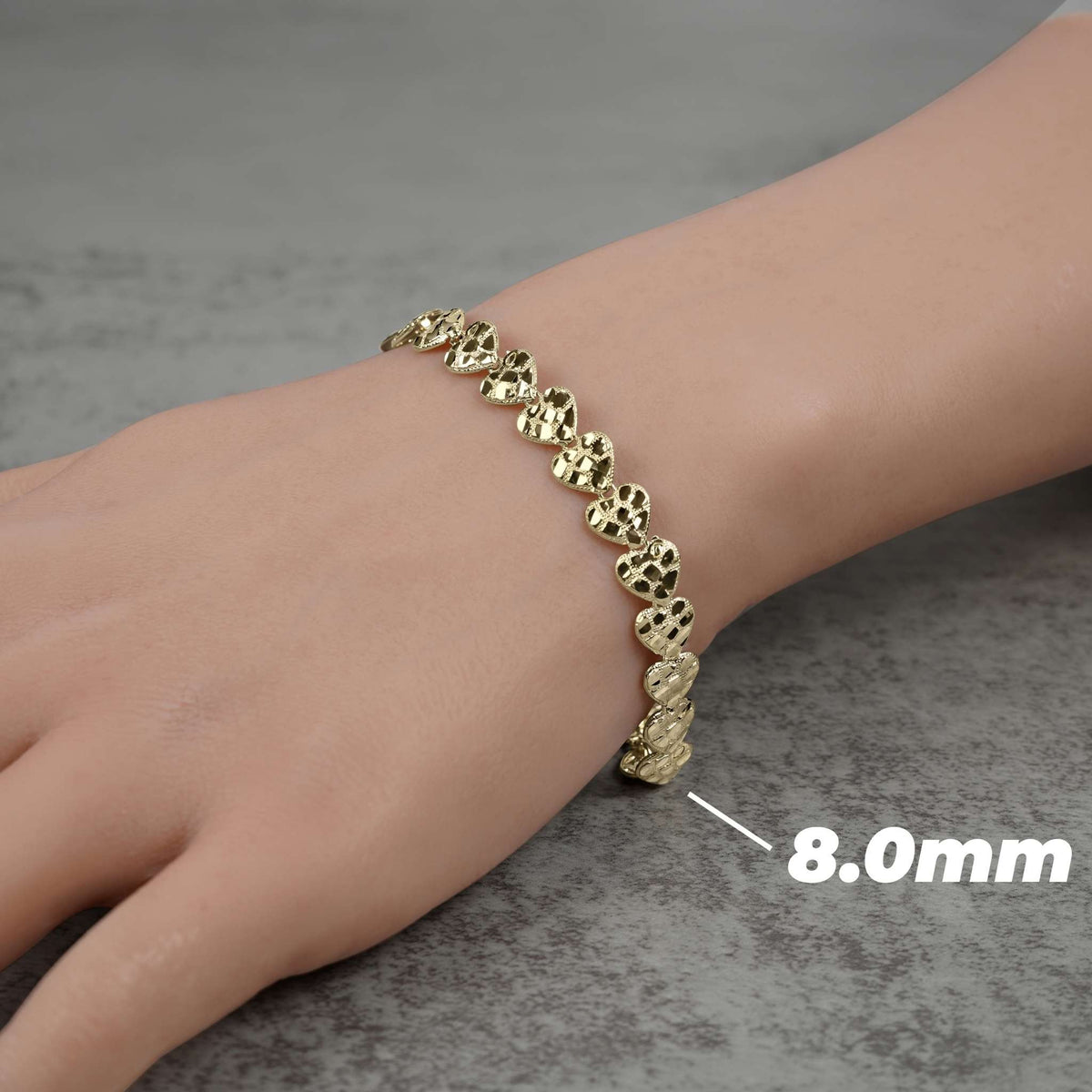 Person wearing an 8.0mm gold concave nugget heart link bracelet on their wrist.
