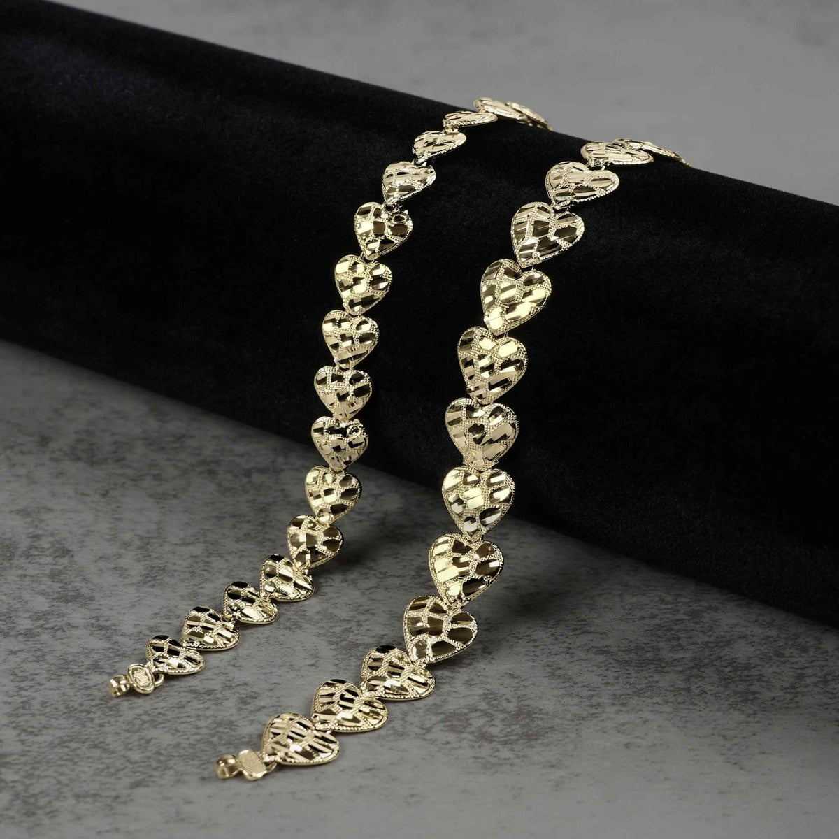 Real solid gold concave nugget heart-shaped link bracelet displayed on dark velvet.