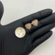 Two-tone gold crucifix heart stud earrings held in a hand for size reference.
