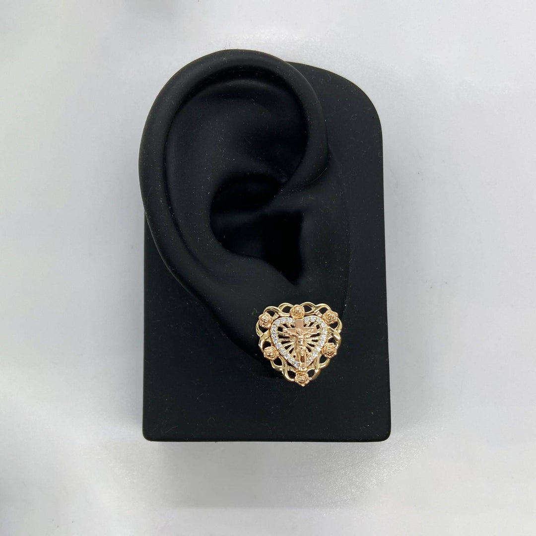 Two-tone gold crucifix and rose heart stud earring displayed on a black ear stand.