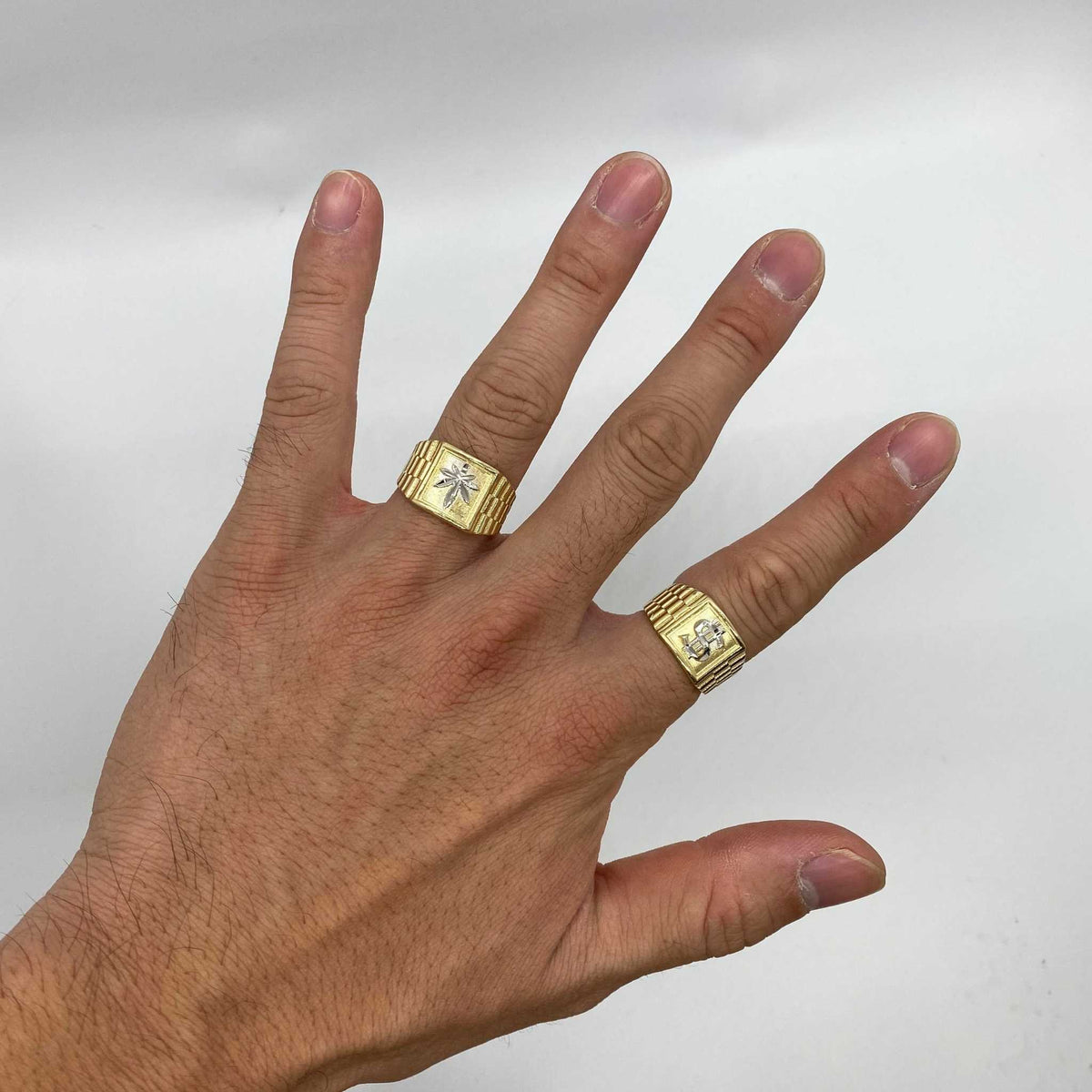 Hand wearing two 10k - 14k gold Rollie Band rings with diamond accents on a white background