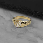 10k 14k yellow gold signet ring with a round face set with clear cubic zirconia stones and a textured band, shown at an angle.