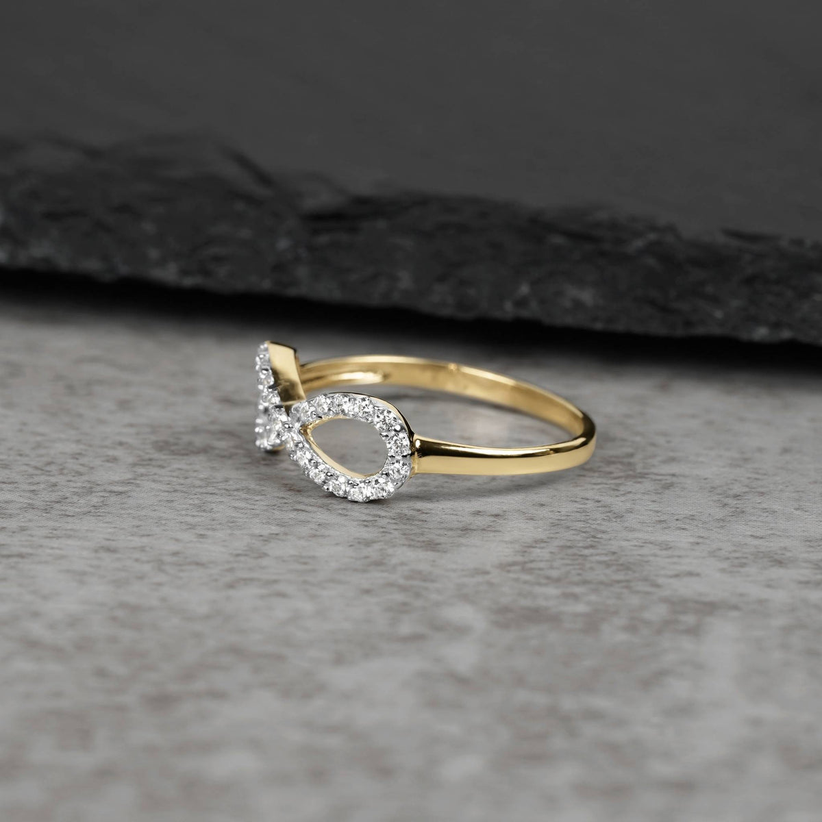 10k or 14k gold Elio infinity CZ ring displayed on a dark slate background.