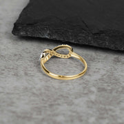 Profile view of the 10k or 14k gold Elio infinity ring on stone surface.