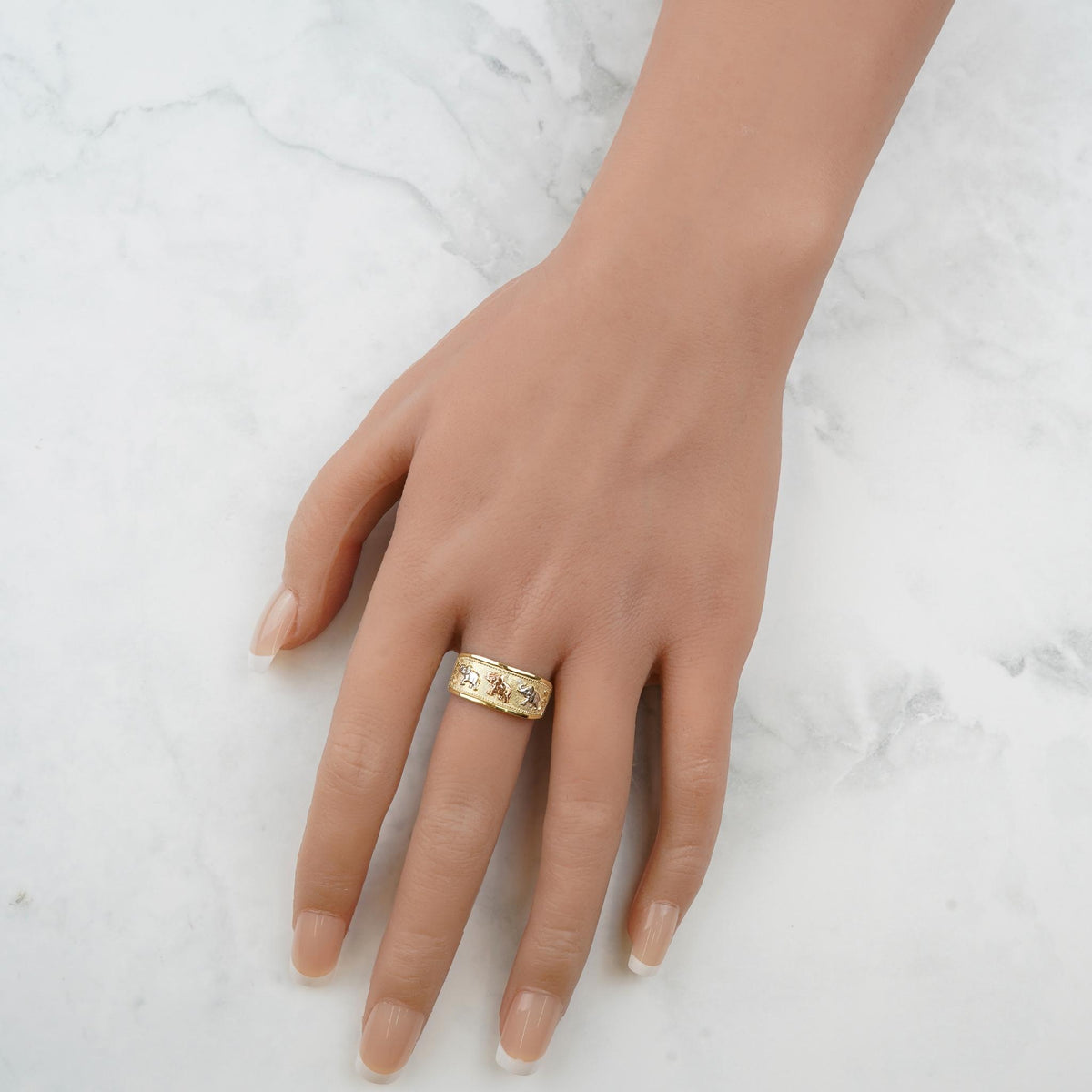 Close-up of a hand modeling the polished tricolor gold lucky elephant ring.