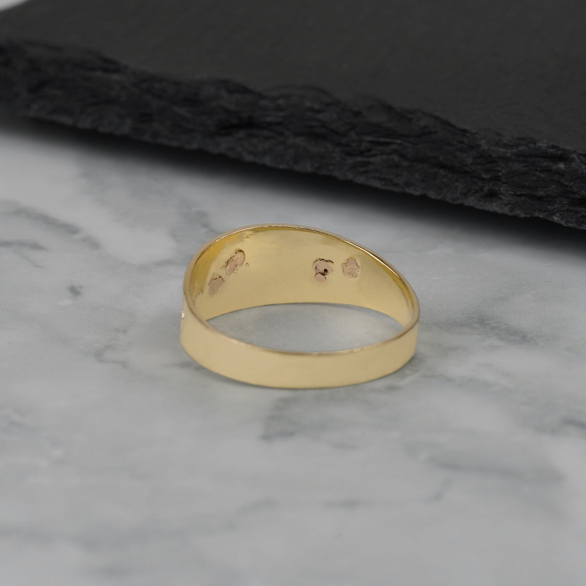 Interior view of the gold ring showcasing hallmark stamps against a dark background.