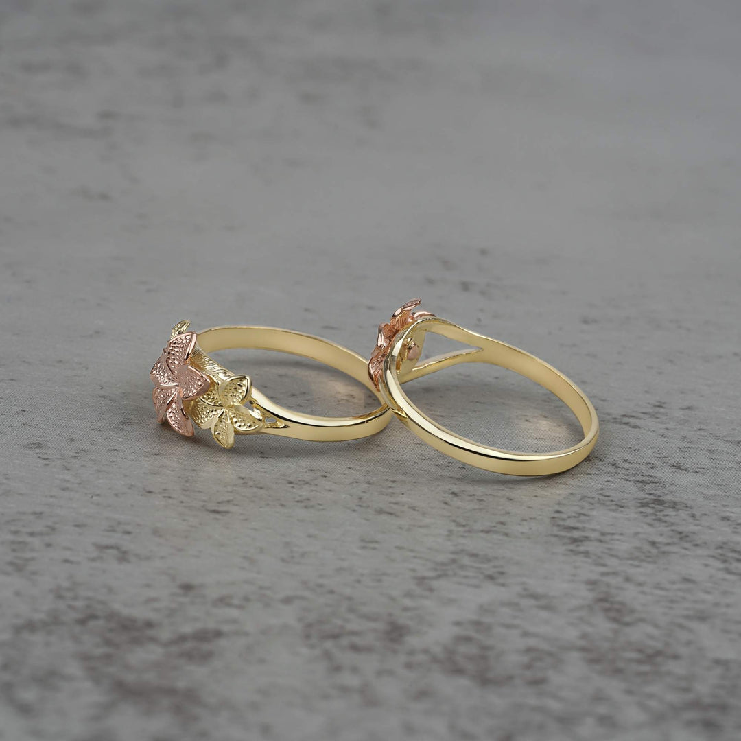 Two 10k - 14k gold rings with floral designs side view on a gray surface