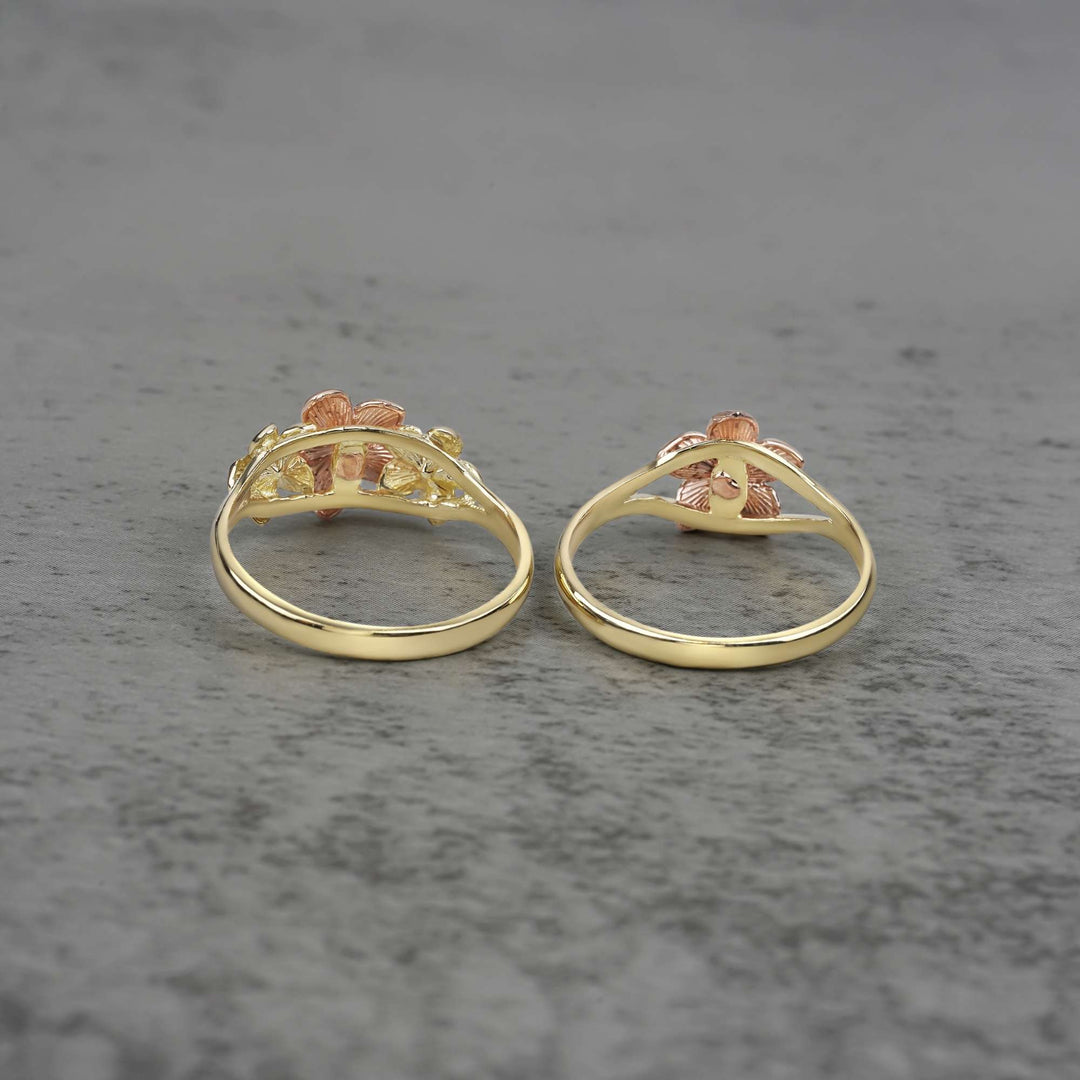 Two 10k - 14k gold rings with floral design back view on a gray surface