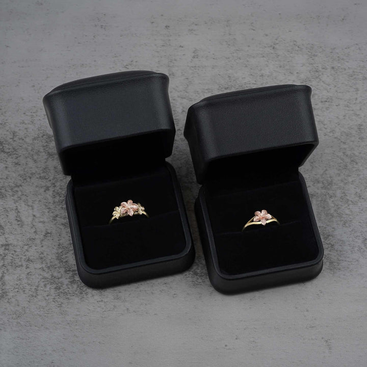 Two black jewelry boxes with two 10k - 14k gold rings with floral design