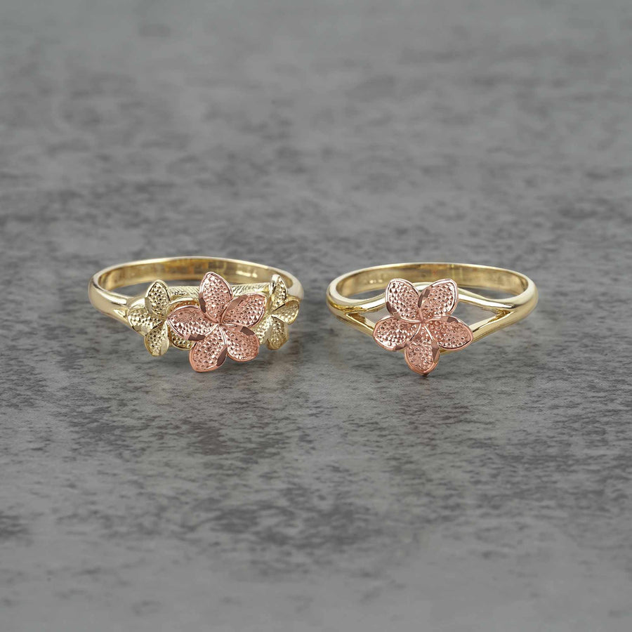 Two 10k - 14k gold and rose gold flower shaped rings on a gray surface