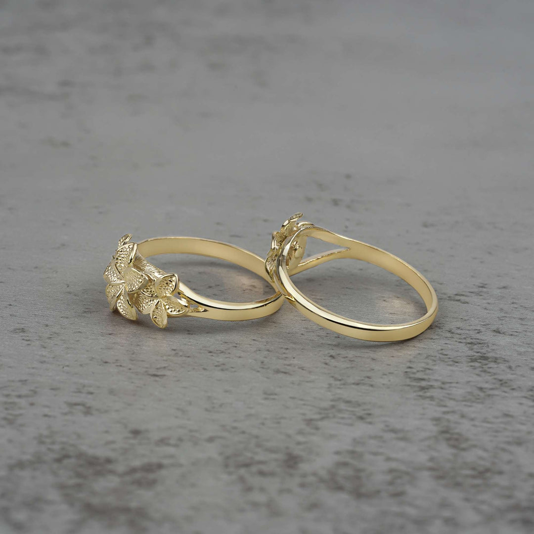 Two 10k - 14k gold rings with floral designs side view on a gray surface