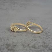 Two 10k - 14k gold rings with floral designs side view on a gray surface