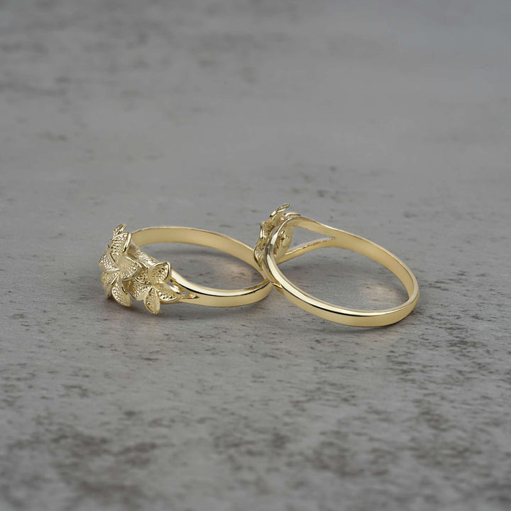 Two 10k - 14k gold rings with floral designs side view on a gray surface