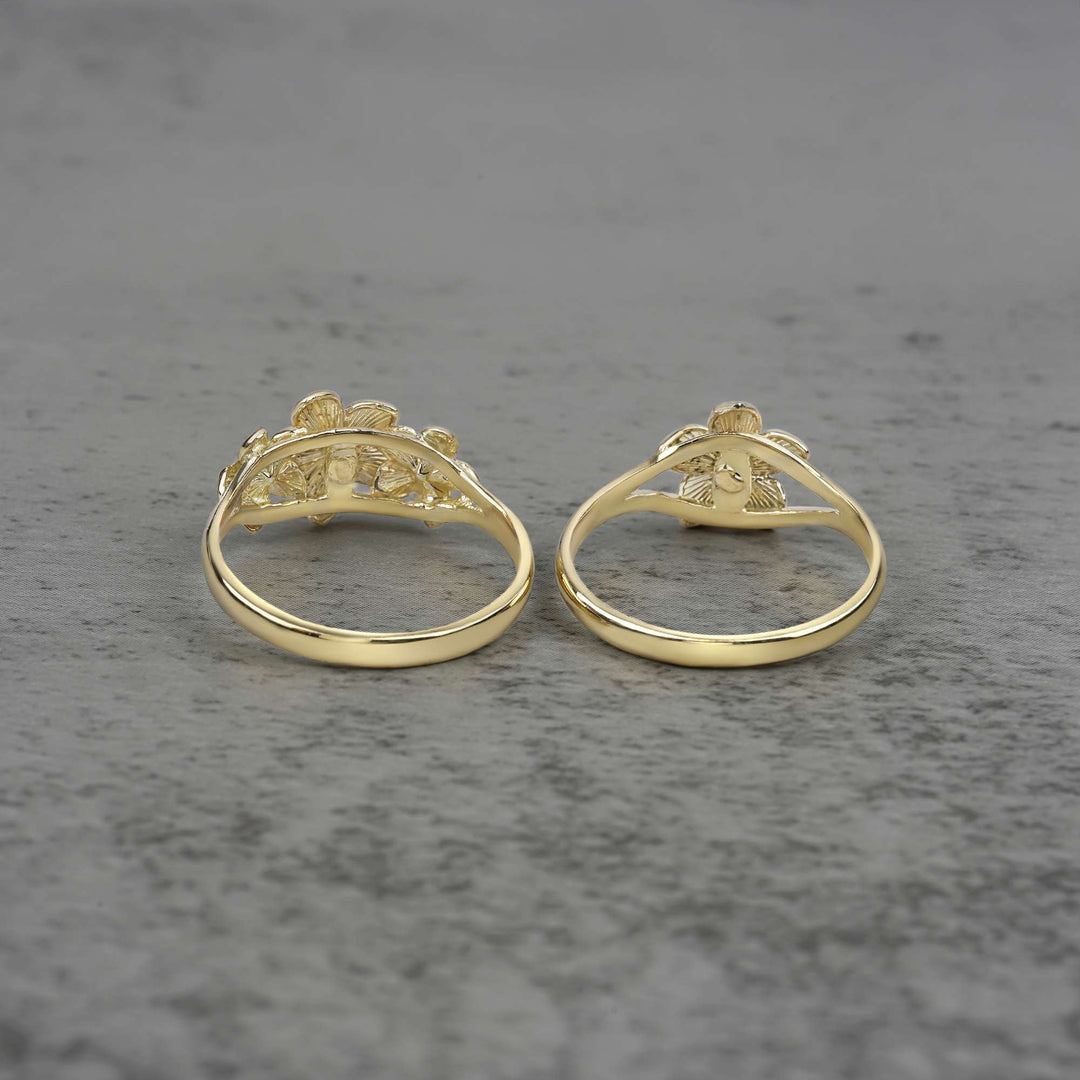 Two 10k - 14k gold rings with a floral design back view on a gray surface