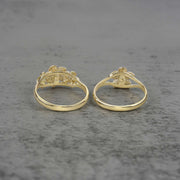 Two 10k - 14k gold rings with a floral design back view on a gray surface