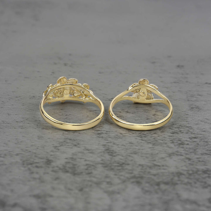 Two 10k - 14k gold rings with a floral design back view on a gray surface