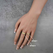 Hand wearing two 10k - 14k gold rings with floral designs on a gray background