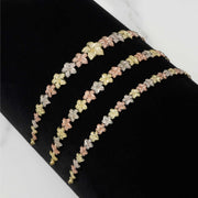 Three gold hibiscus flower bracelets in varying widths displayed on a black surface.