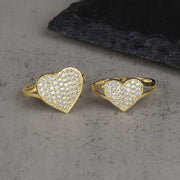 Two 10k-14k gold heart-shaped rings encrusted with white cubic zirconia stones on stone.