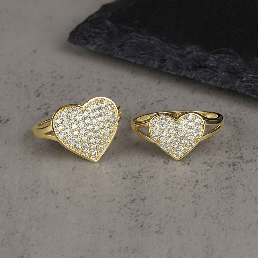 Two 10k-14k gold heart-shaped rings encrusted with white cubic zirconia stones on stone.