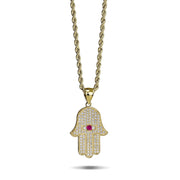 Gold Hamsa hand pendant necklace with cubic zirconia stones and a central pink gemstone.